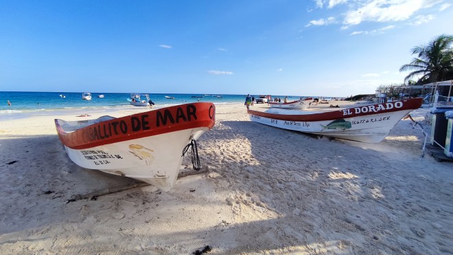 Sonnecchianti barche di legno arenate sulla sabbia bianca a Tulum